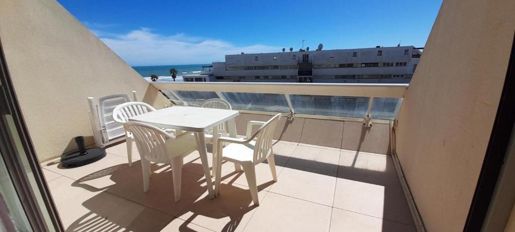 un balcon avec une table et des chaises et l'océan dans l'établissement Studio 10, Héliopolis D au village naturiste, au Cap d'Agde