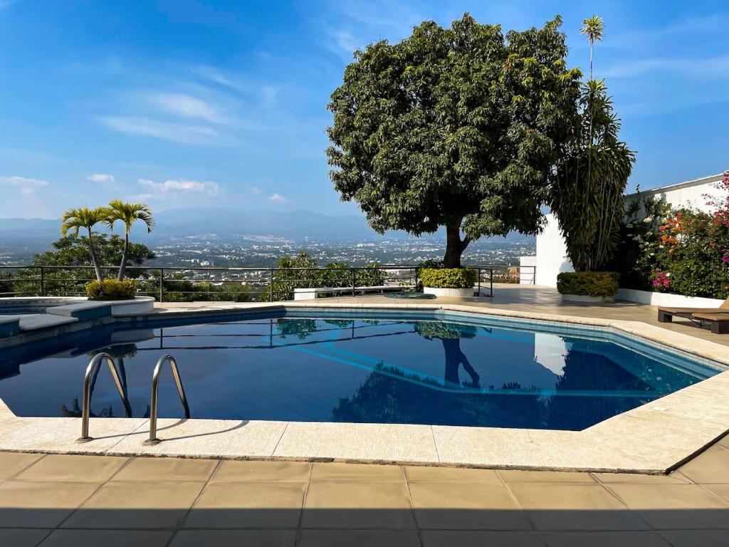 ein Schwimmbad mit einem Baum im Hintergrund in der Unterkunft Casa Lomas de Cuernavaca in Jiutepec