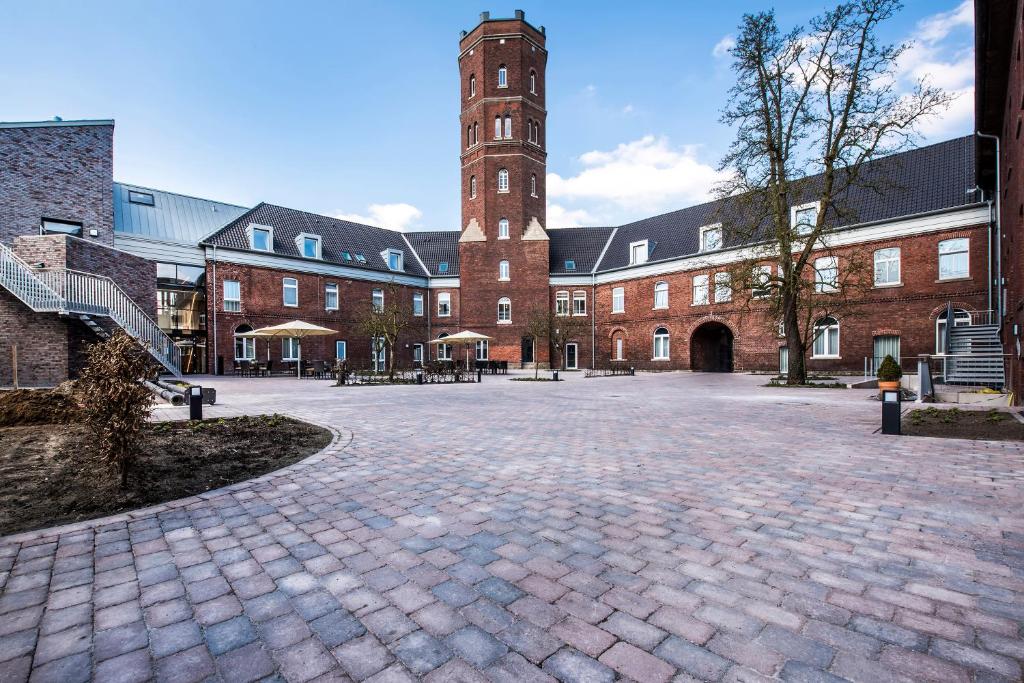 ein großes Backsteingebäude mit einem Uhrturm in der Unterkunft Alexianer Hotel am Wasserturm in Münster