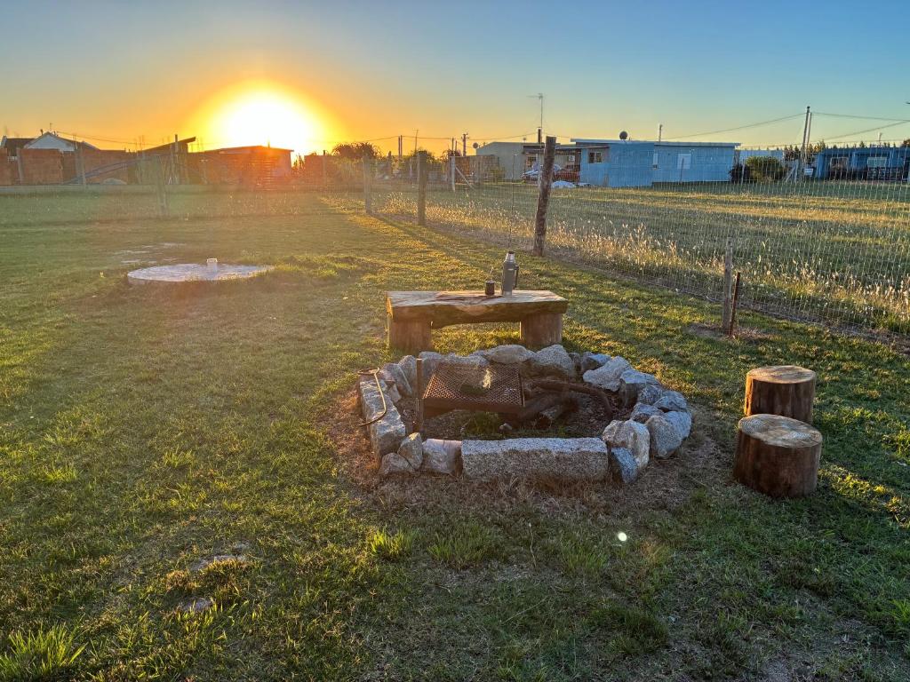 a fire pit in a field with the sunset in the background at Las andinas in Carmelo