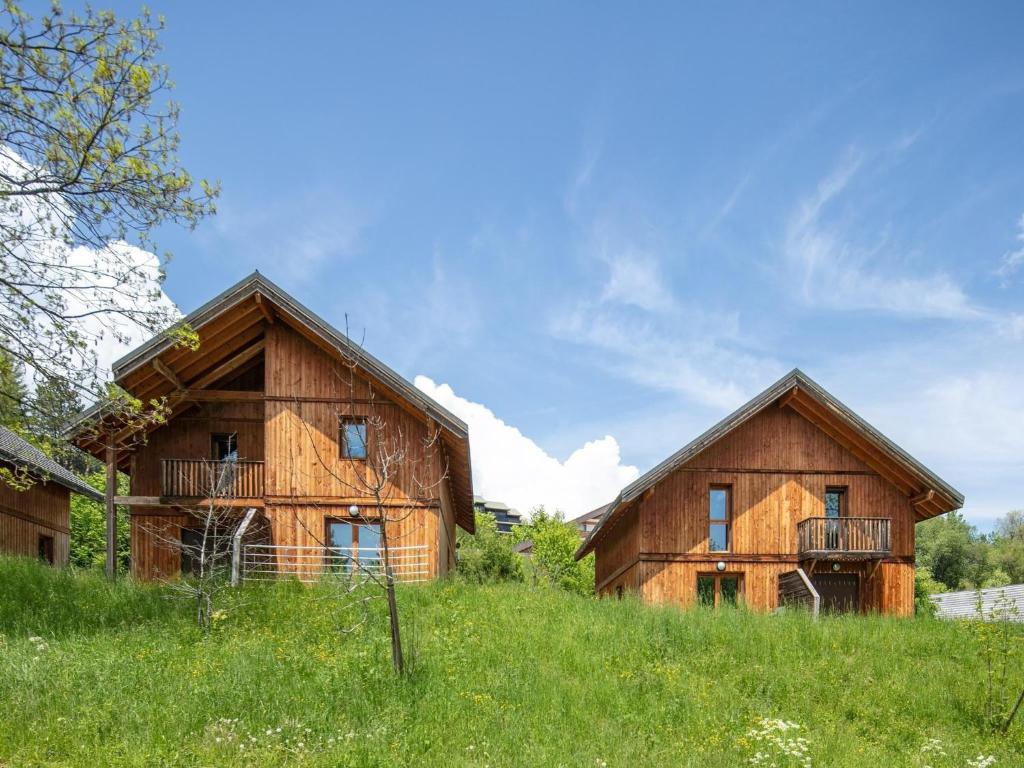 two wooden houses in a field with green grass at Chalet with shuttle bus in Gresse in Gresse-en-Vercors