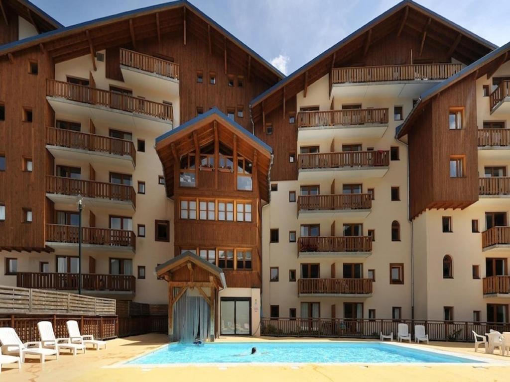 un immeuble d'appartements avec une piscine devant dans l'établissement Valfréjus Chalet w Pool, à Valfréjus