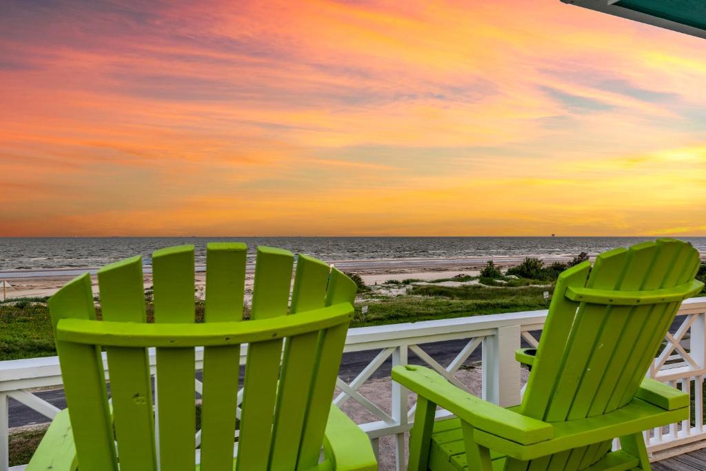 zwei grüne Stühle am Strand bei Sonnenuntergang in der Unterkunft Holiday Hideaway in Bolivar Peninsula