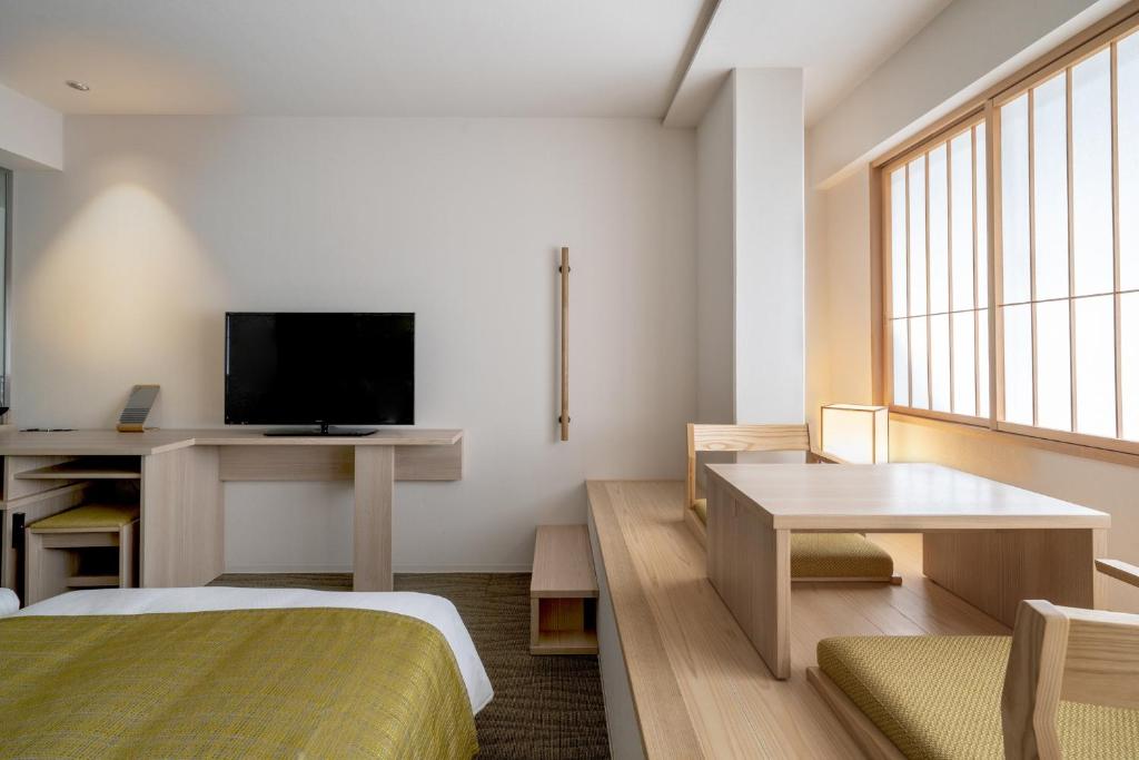 a room with a bed and a desk and a television at Hotel Vista Premio Kyoto Nagomi tei in Kyoto