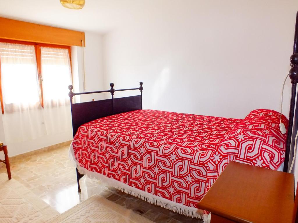 a bedroom with a bed with a red and white comforter at Casa Anni '70 in Burgos