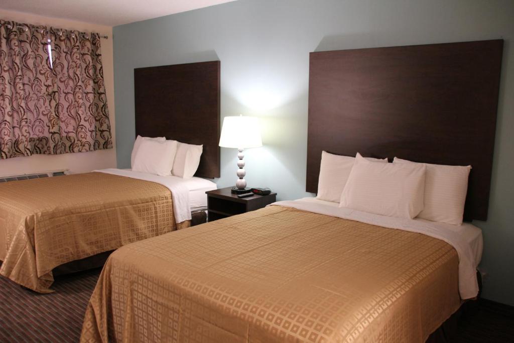 a hotel room with two beds and a lamp at Sterling Inn near IAG Airport in Niagara Falls