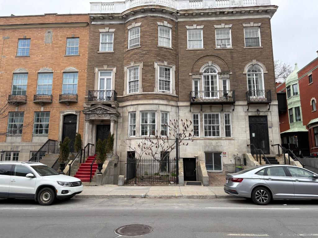 two cars parked in front of a large brick building at Authentic Spacious 1BDR In Downtown Montreal in Montréal