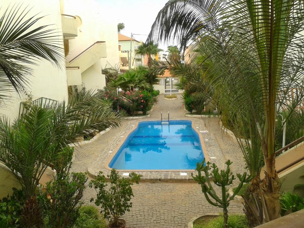 a swimming pool in a courtyard with palm trees at Apartamento T3 encantador com piscina wifi e perto de praia in Santa Maria