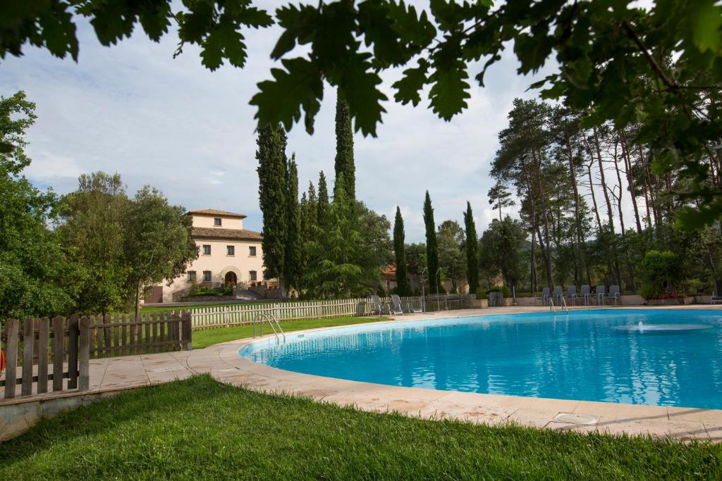 una piscina en un patio con una casa al fondo en La Torre del Vilar, en Santa Eulàlia de Riuprimer
