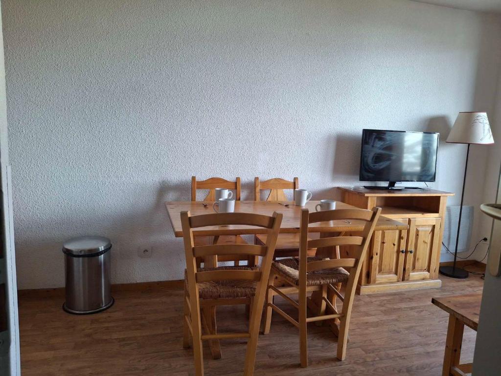 une table à manger avec des chaises et une télévision dans l'établissement Saint-François-Longchamp, T3 confortable, 6 pers, proche pistes - FR-1-807-120, à Saint-François-Longchamp