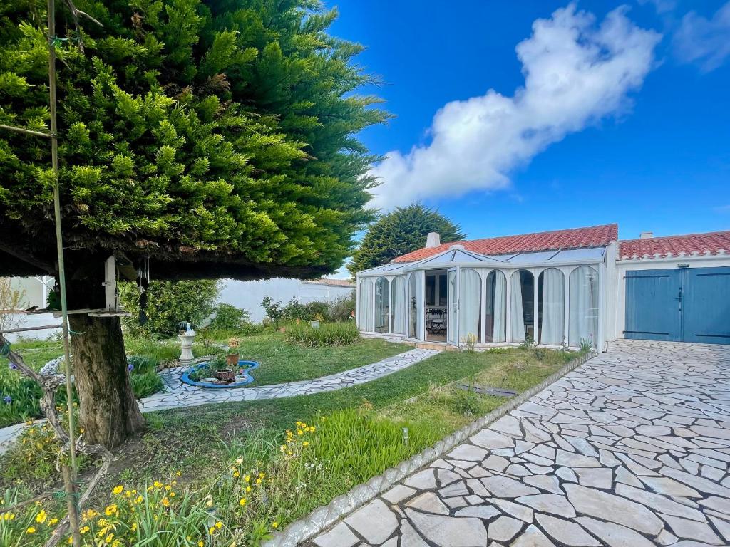un jardin avec une maison et un arbre dans l'établissement Maison calme à 400m de la mer, véranda, jardin - FR-1-231-337, à Bretignolles-sur-Mer