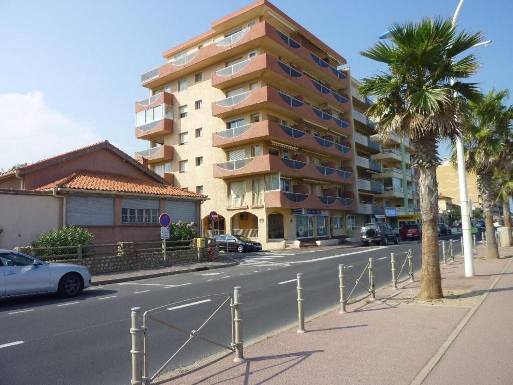 un bâtiment sur le côté d'une rue bordée de palmiers dans l'établissement Deux-Pièces Front de Mer pour 4 Pers à Canet-Plage - FR-1-750-107, à Canet