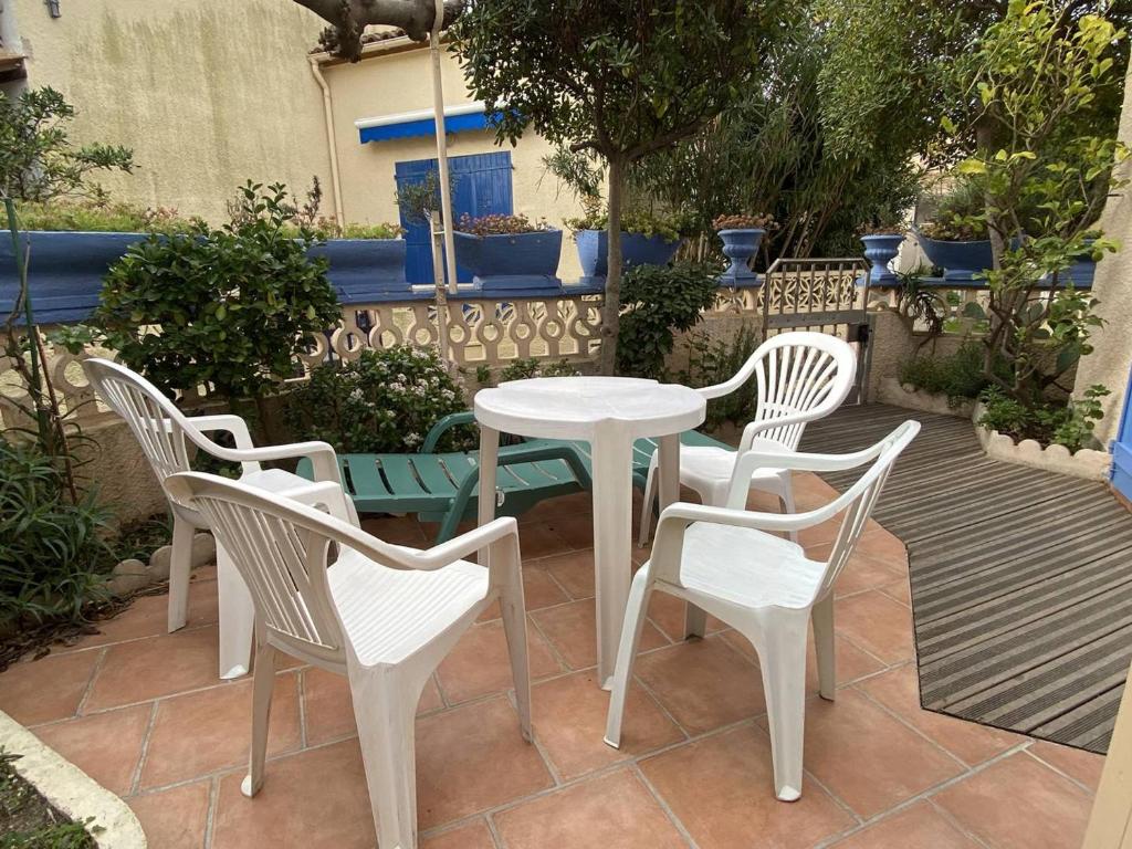 une table blanche et quatre chaises sur la terrasse dans l'établissement Villas paisibles à 400m de la plage pour 4 personnes - FR-1-750-104, à Canet