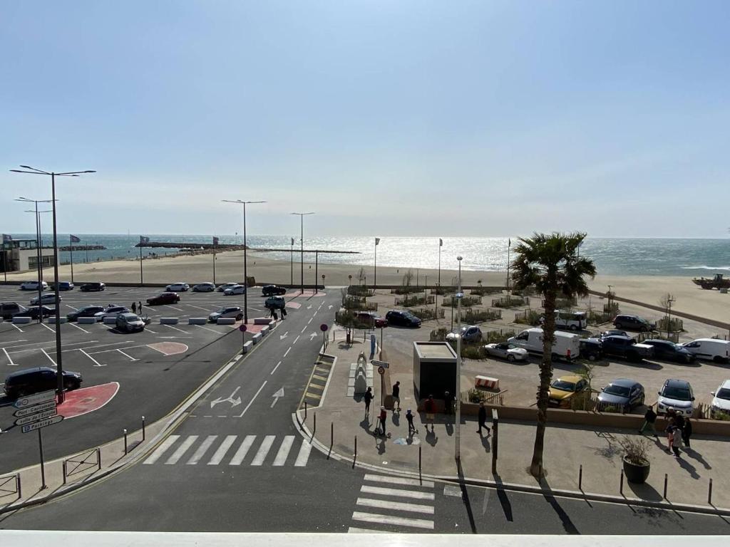 une rue avec un parking à côté de la plage dans l'établissement Trois-pièces 3* face mer, centre Canet-Plage - FR-1-750-117, à Canet