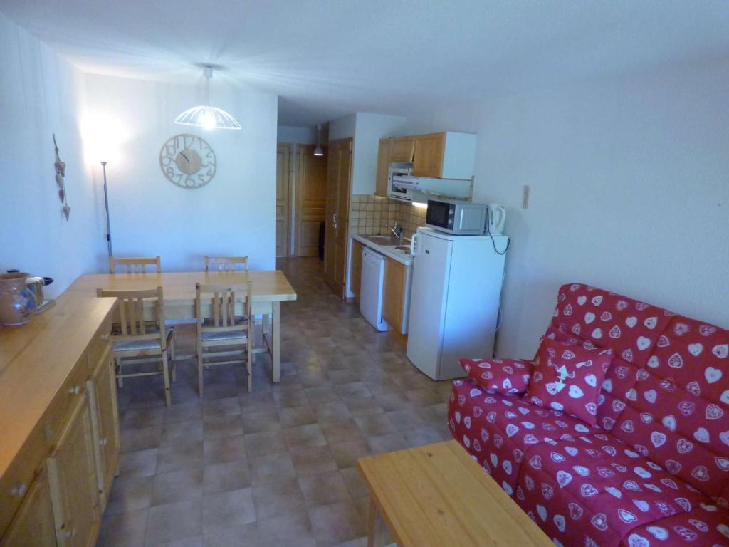 un salon avec un canapé rouge et une cuisine dans l'établissement Charmant T3 ski aux pieds, 6 pers, balcon, garage - FR-1-458-217, au Grand-Bornand