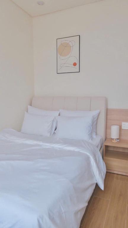 a bed with white sheets and a picture on the wall at At De June 204 in Cu Lao Thu