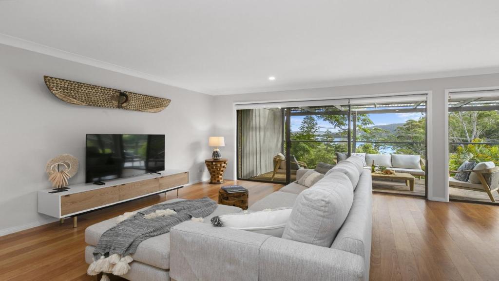 a living room with a couch and a tv at 'Bay Dreams at Killcare' by HolidayCo in Killcare