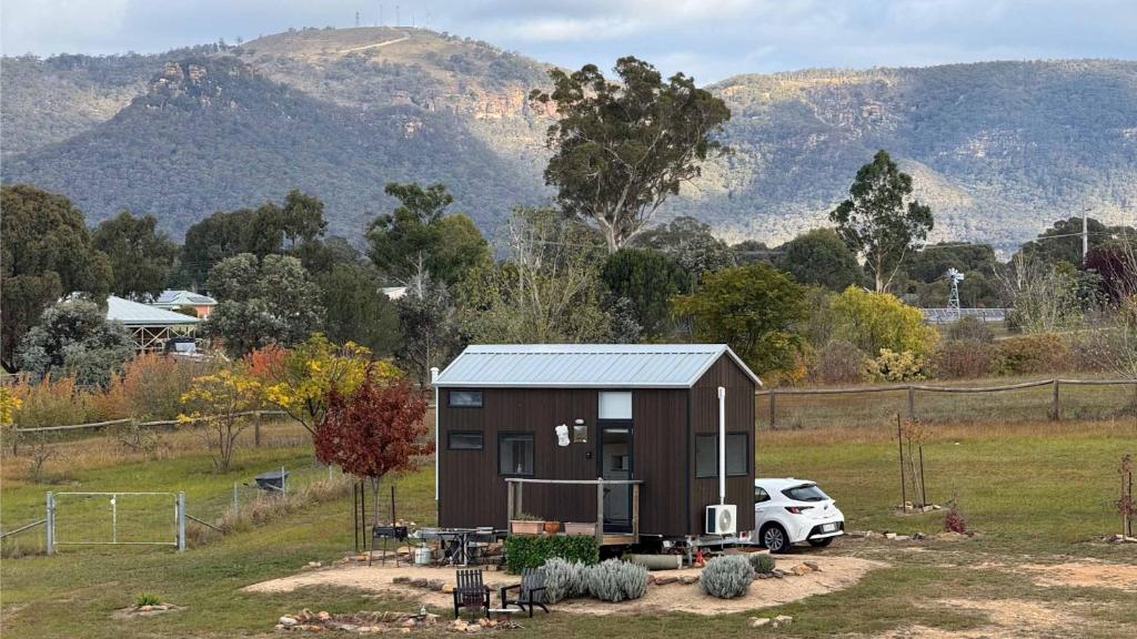a small house with a car parked in a field at Little Lady Cabin by Tiny Away in Rylstone