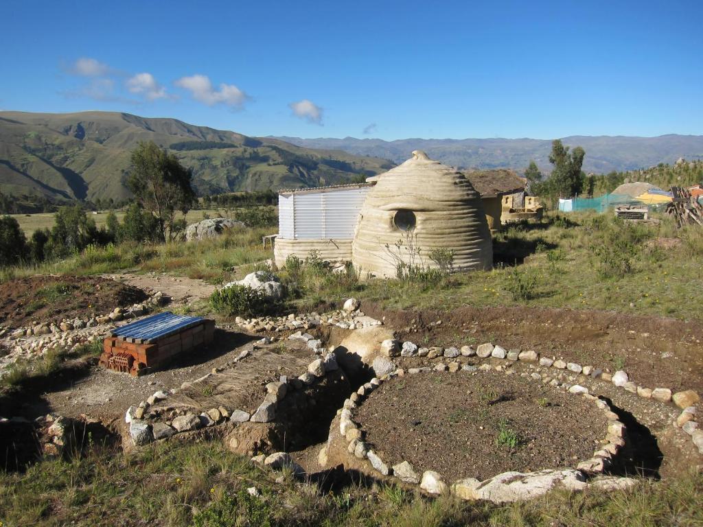 a field with a barn and a building with a stone wall at Andean Mountains Hostel in Huaraz