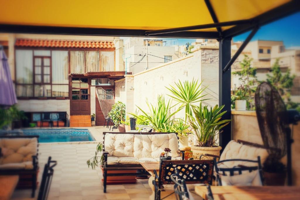 a patio with a couch and a table and a pool at Narcisa Farmhouse B&B in Nadur