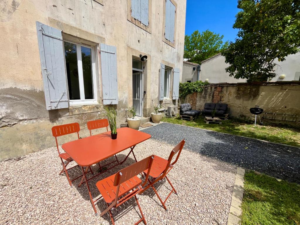 czerwony stół i krzesła przed domem w obiekcie Le Riquet - Parking et jardin privé, clim, RDC w mieście Castelnaudary