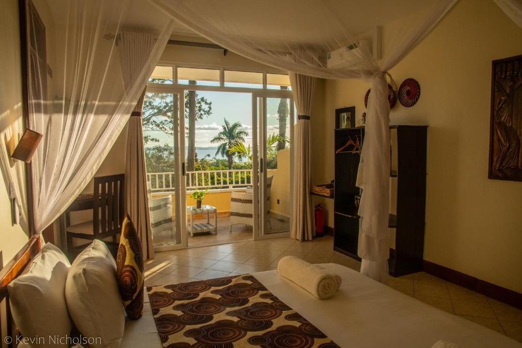 a bedroom with a bed and a view of a balcony at Karibu Entebbe in Entebbe