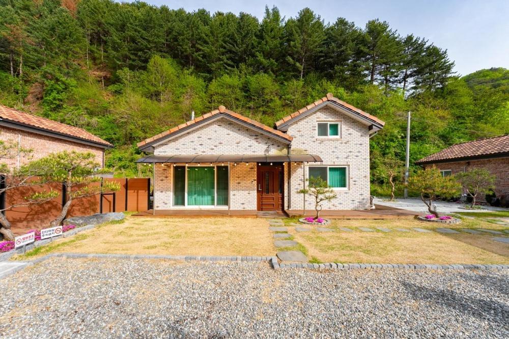a house with a large yard in front of it at Chuncheon Soopsog Jageun Jib Pension in Chuncheon