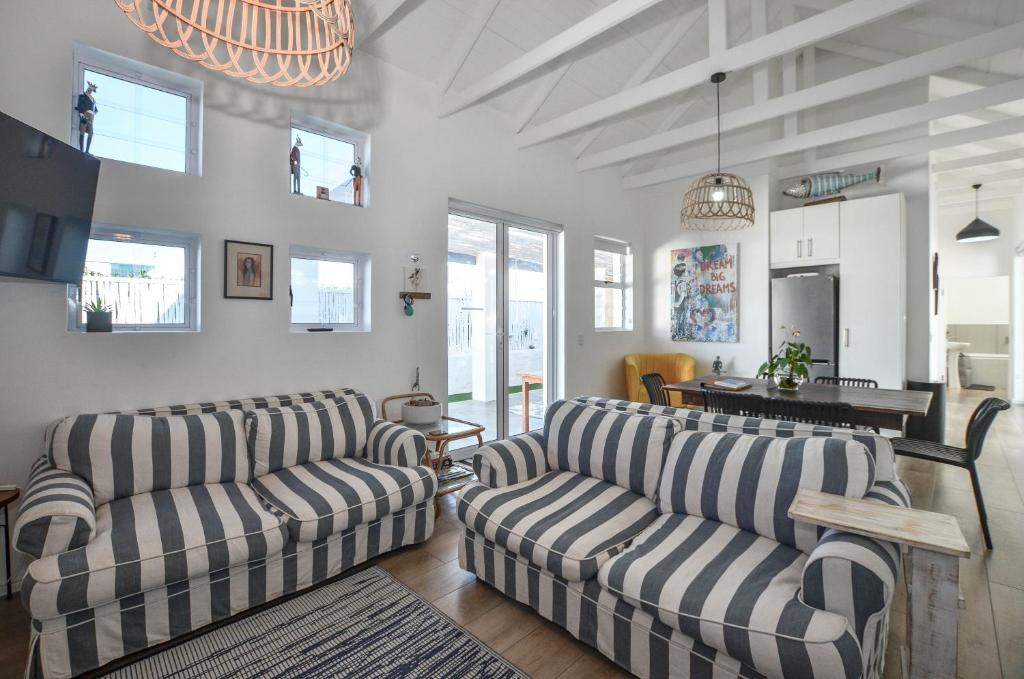 a living room with two couches and a table at Cozy Holiday Cottage - XX Cottage Yzerfontein in Yzerfontein