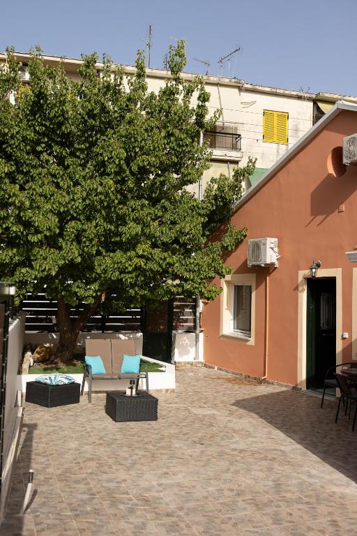 a courtyard with a tree and chairs and a building at Artemis House Corfu Town in Ágios Rókkos