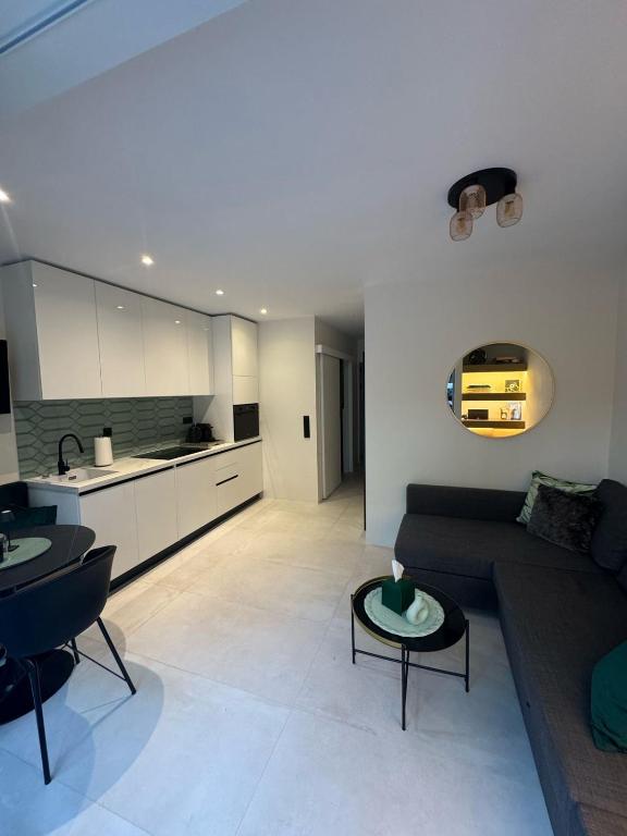 a living room with a couch and a kitchen at Cosy apartment with shared pool and garden in Athens