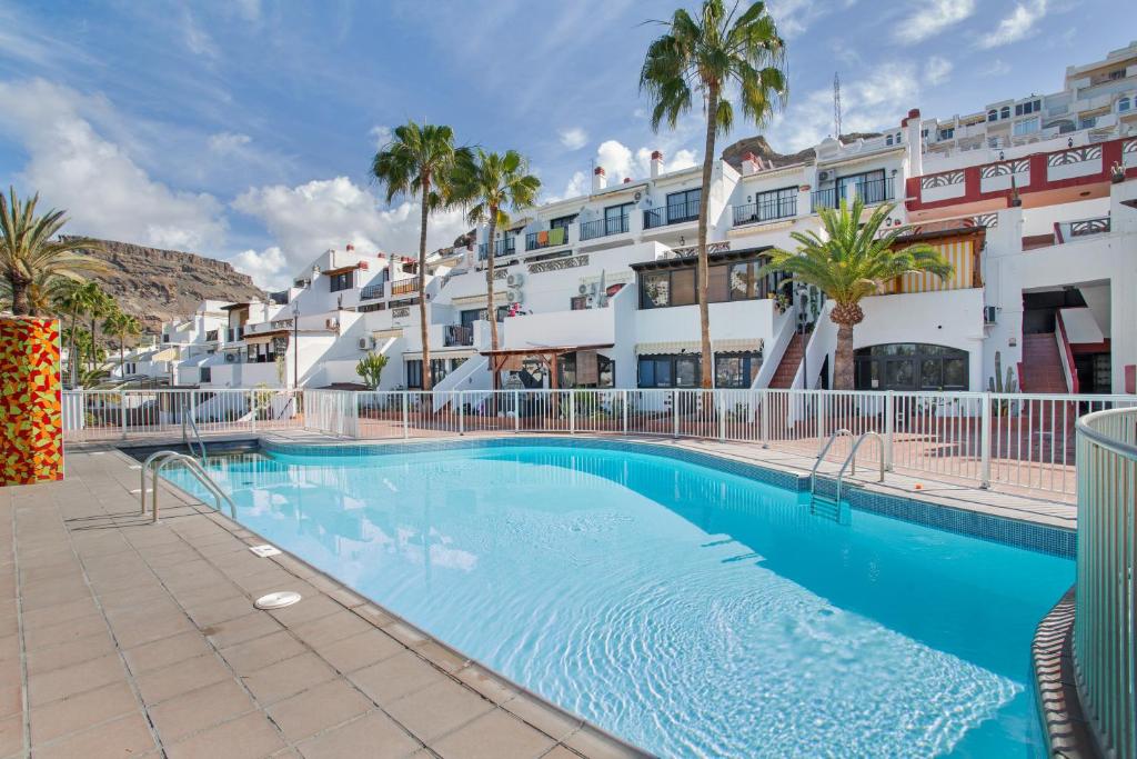 a swimming pool in front of a building with palm trees at Daniel House in Mogán