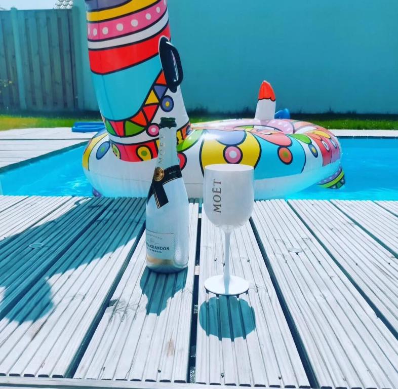 a bottle of wine and a glass on a table next to a pool at Unieke landelijke woning met zwembad in Kranenburg