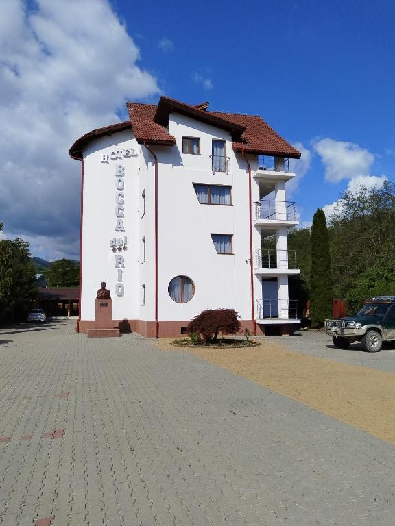 a white building with a sign on the side of it at Pensiunea Bocca Del Rio in Gura Râului