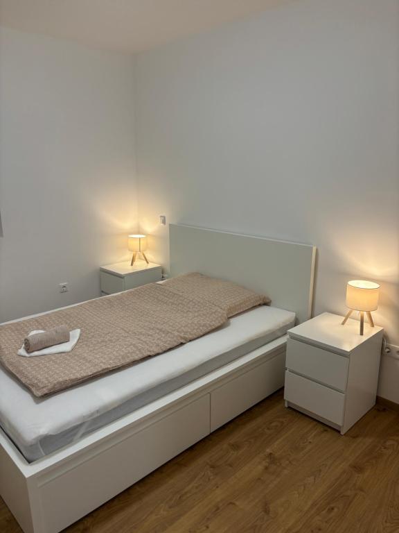 a white bedroom with a bed and two night stands at AA Apartman - Balatonboglár in Balatonboglár