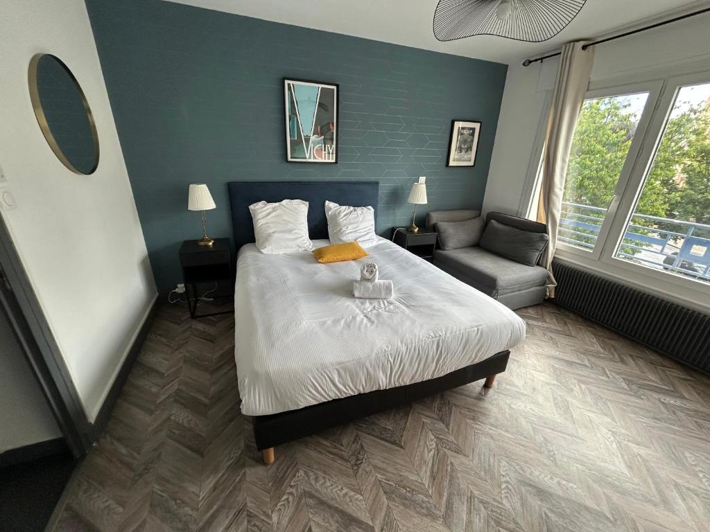une chambre avec un lit, un canapé et une chaise dans l'établissement Appartement prince de galles, à Vichy