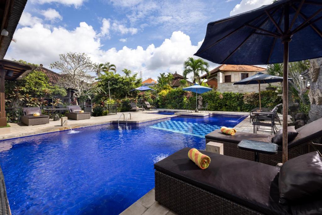 ein Pool mit einem Sonnenschirm, einigen Stühlen und einem Sonnenschirm in der Unterkunft Taman Harum Cottages in Ubud