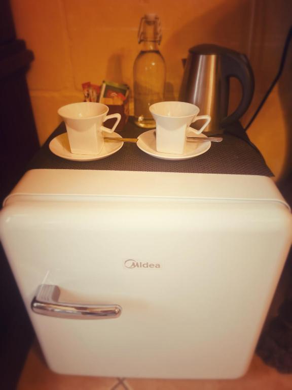 two cups and saucers sitting on top of a refrigerator at Narcisa Farmhouse B&B in Nadur