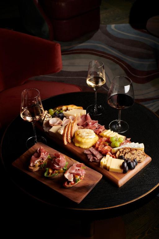 a table with two glasses of wine and a plate of food at FIVE Zurich - Luxury City Resort in Zürich