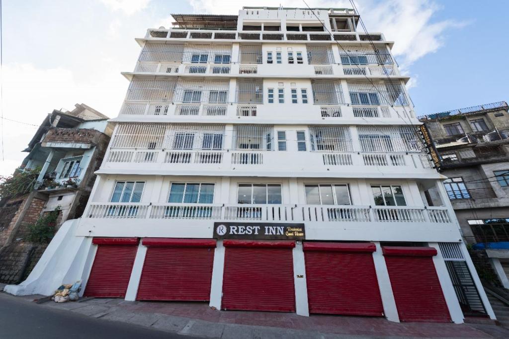a tall white building with red doors on a street at Rest Inn Hotel in Jāmb