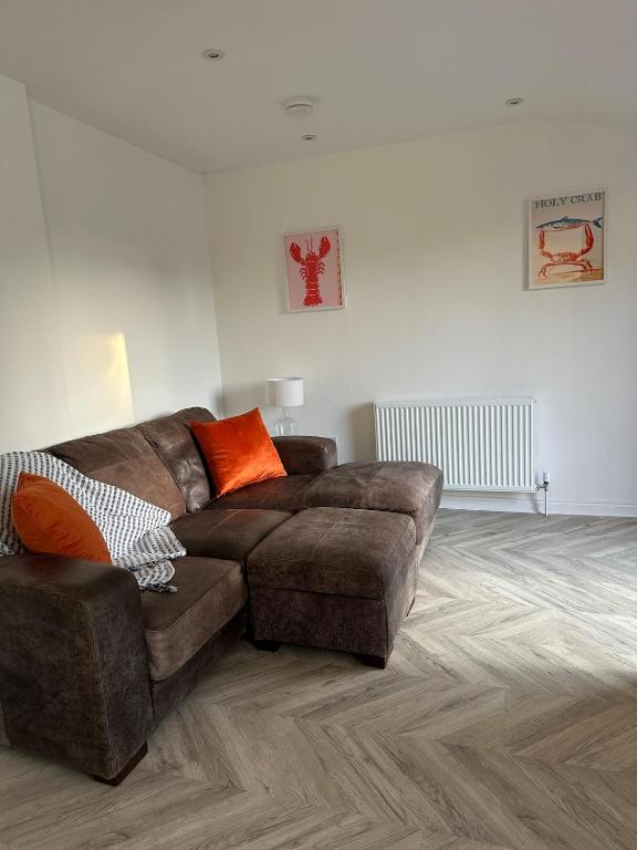 a living room with a brown couch and orange pillows at Casa Sands in Spittal