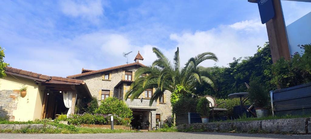 a house with a palm tree in front of it at La Casona del Carmen in Noja
