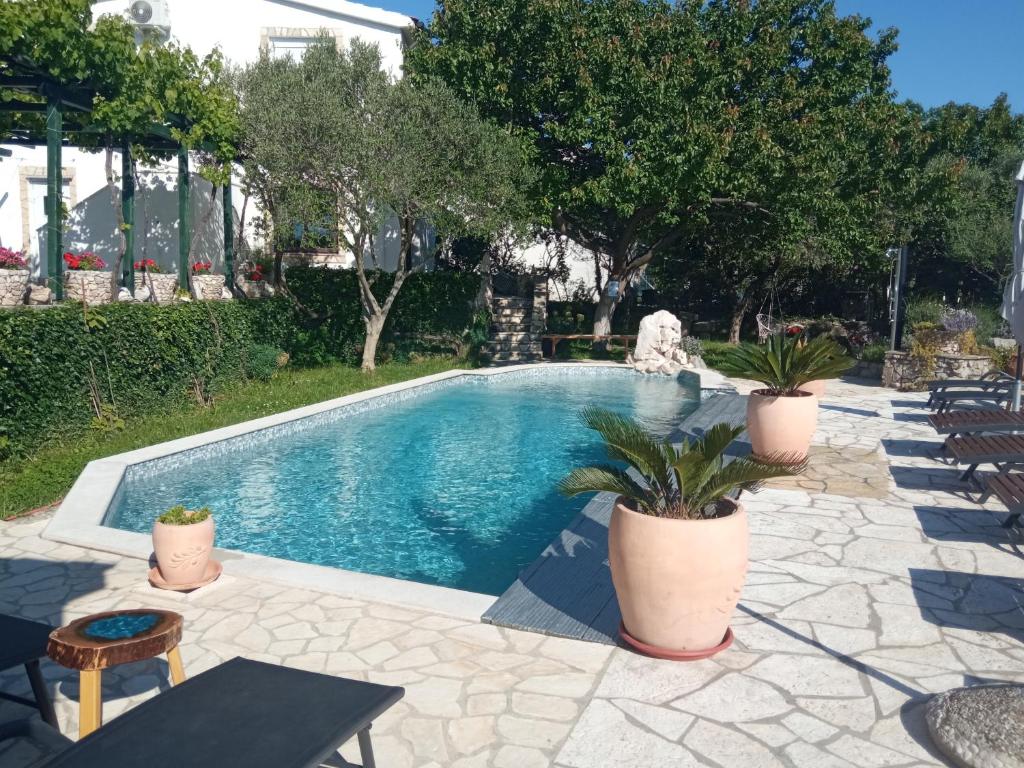 a swimming pool with potted plants on a patio at KATY&MLADEN in Baška