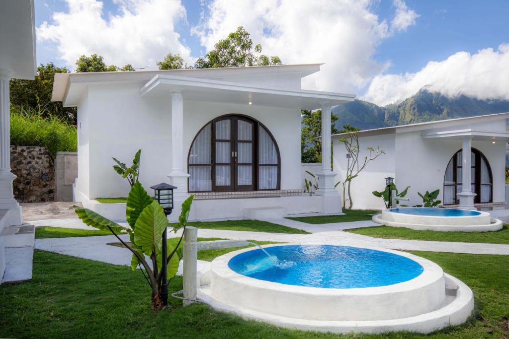 a white house with a swimming pool in the yard at Kamaru Villa Kintamani in Kintamani