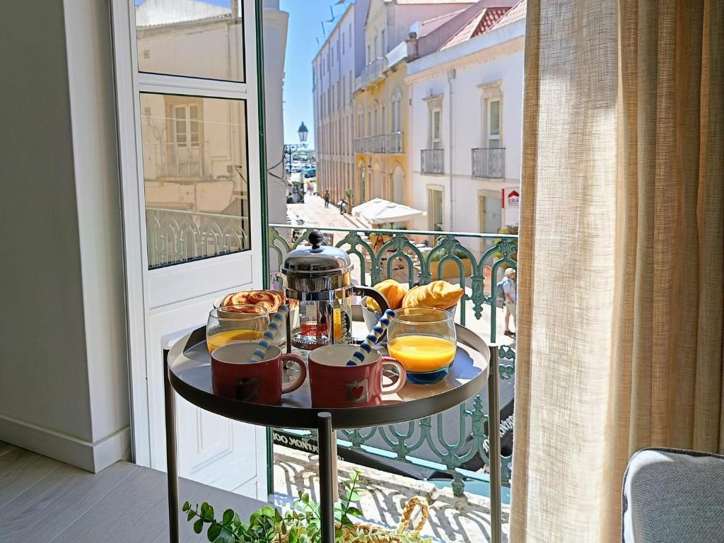 a table with drinks and orange juice on a balcony at Grey and Green, modern 2-bedroom apartment, AC, top location at faro's historic centre in Faro