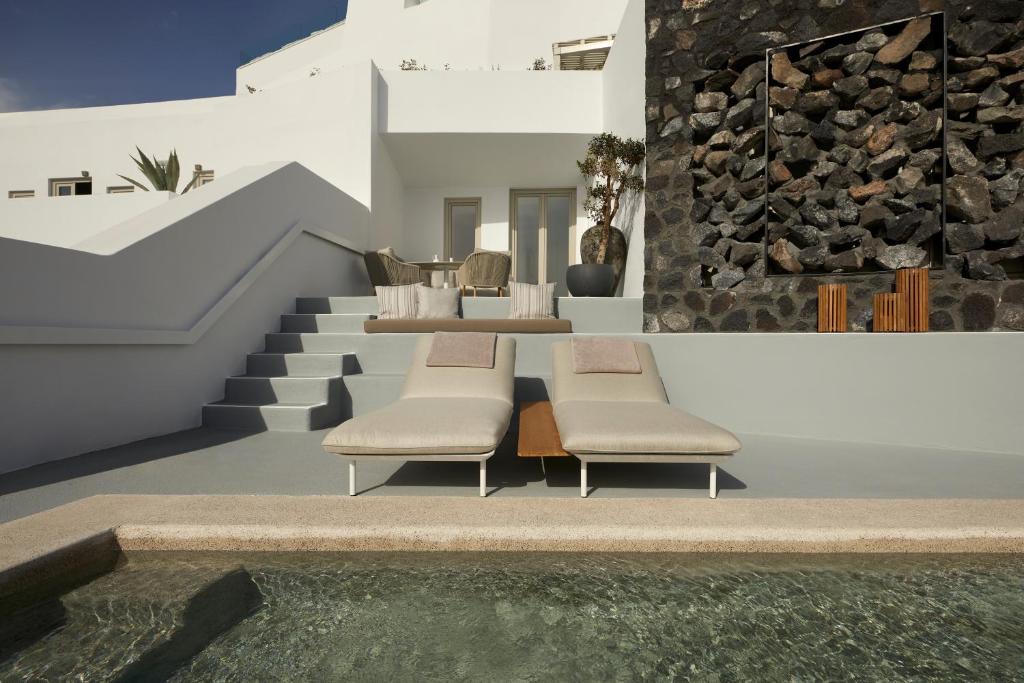 una casa con due sedie e una piscina di Grace Hotel, Auberge Resorts Collection a Imerovigli