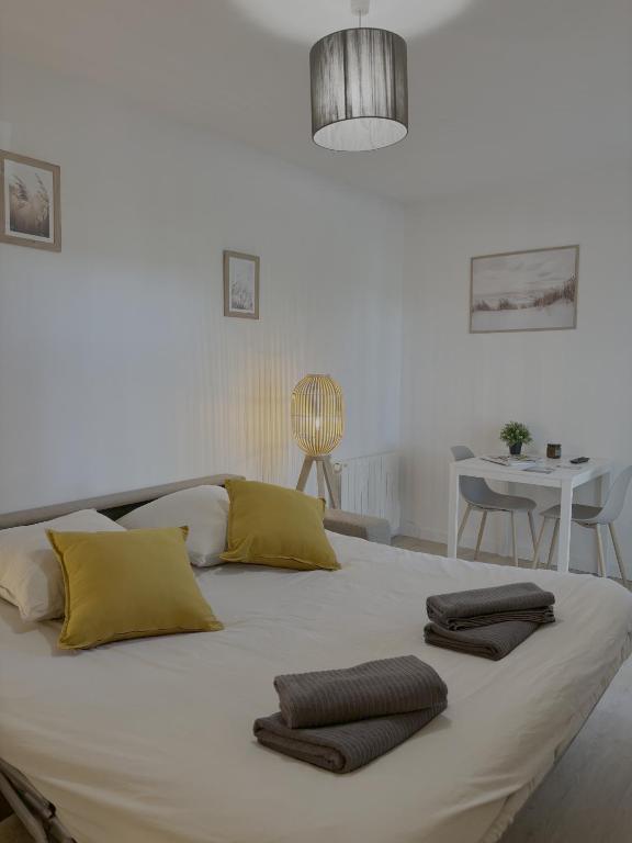 - un grand lit blanc avec 2 oreillers bruns dans l'établissement Loft 4, à Saint-Gély-du-Fesc