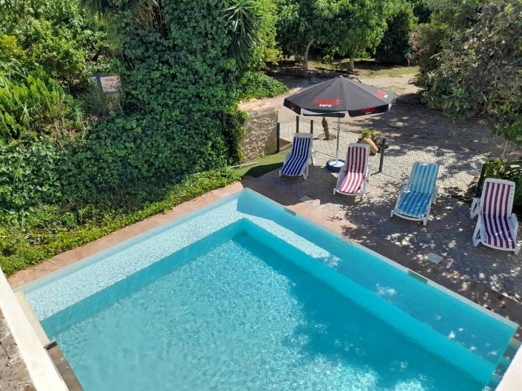 an overhead view of a swimming pool with two chairs and an umbrella at Quinta do Pomarinho with private pool in Tavira