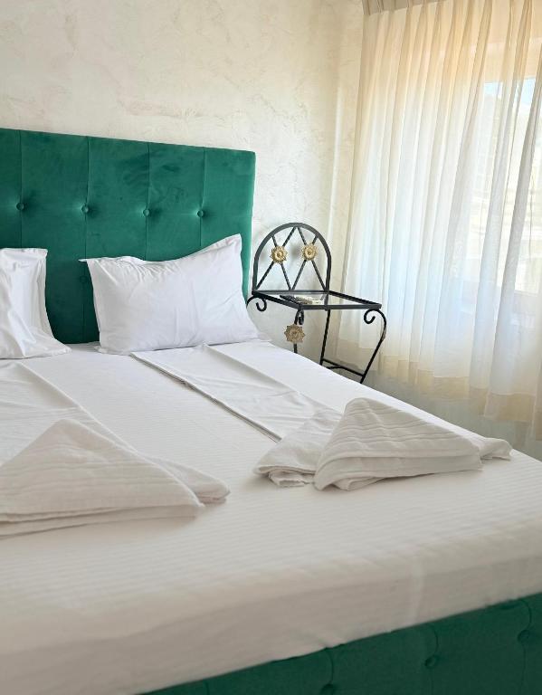 a large white bed with a green headboard and white pillows at Pensiunea Diamond in Eforie Nord