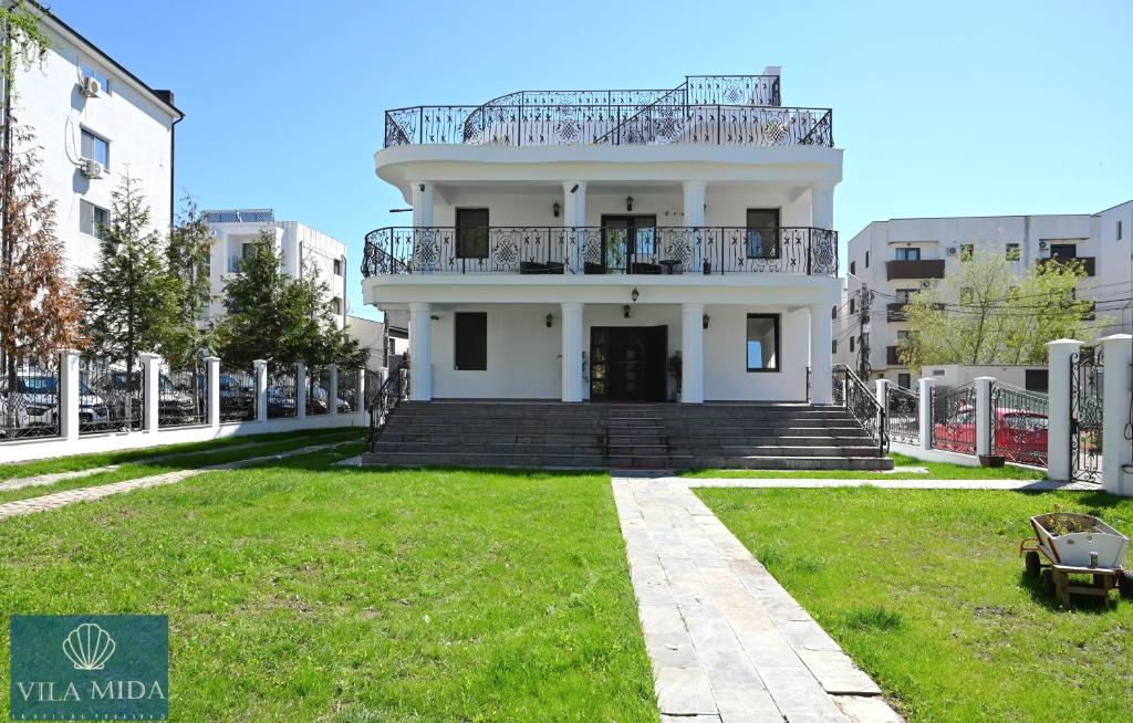 a white house with a balcony on top of a yard at Mida Summer Villa in Mamaia Sat/Năvodari