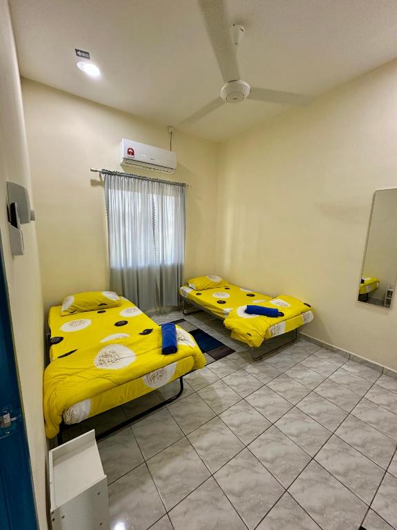 two beds in a room with yellow sheets at Teratak Manis Homestay in Kuantan